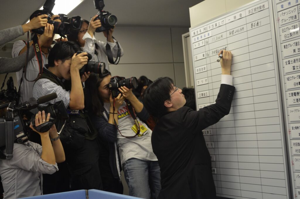 A JCM staff member writes a wage increase response on a whiteboard
