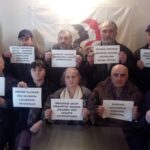 Georgian mine workers hold up posters with their demands to the government and the company.