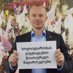 Jyrki Raina, general secretary of IndustriALL Global Union, holds poster in solidarity with Georgian miners